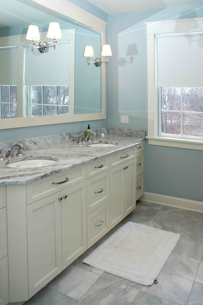 Imagen de cuarto de baño principal moderno de tamaño medio con lavabo bajoencimera, armarios con paneles empotrados, puertas de armario blancas, encimera de mármol, baldosas y/o azulejos blancos, paredes azules y suelo de mármol