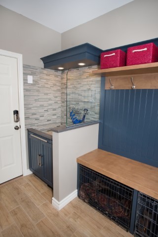 Small dog shower is raised above a short blue cabinets.  Next to that is a bench with blue paneling 