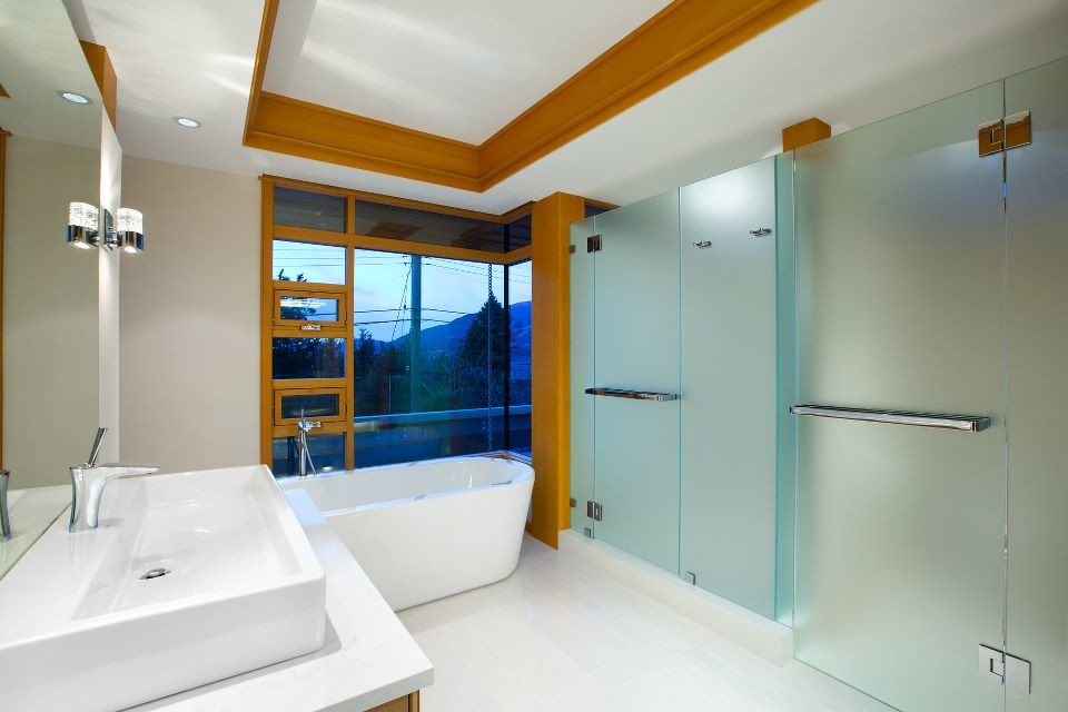 На фото: большая главная ванная комната в современном стиле с отдельно стоящей ванной, душевой комнатой, унитазом-моноблоком, белой плиткой, белыми стенами, полом из керамогранита, настольной раковиной и столешницей из искусственного кварца