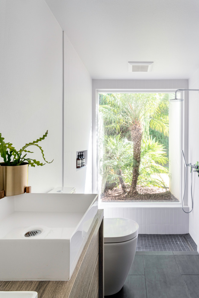 Inspiration for a mid-sized modern master white tile and porcelain tile porcelain tile and black floor bathroom remodel in Orange County with flat-panel cabinets, light wood cabinets, a one-piece toilet, white walls, a vessel sink, wood countertops and white countertops