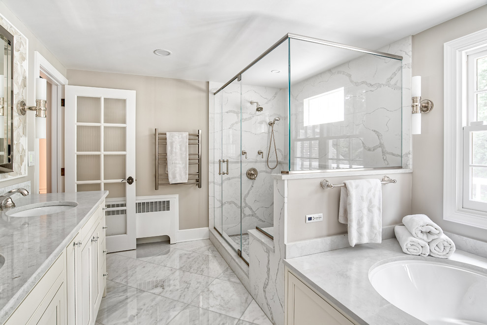 Klassisk inredning av ett stort vit vitt en-suite badrum, med luckor med profilerade fronter, ett undermonterat badkar, vit kakel, mosaik, marmorgolv, ett undermonterad handfat, bänkskiva i kvartsit, vitt golv och dusch med gångjärnsdörr