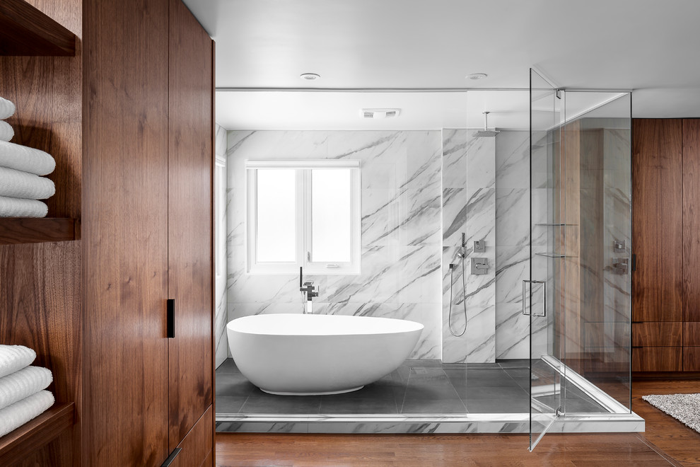 Large contemporary ensuite wet room bathroom in Toronto with flat-panel cabinets, medium wood cabinets, a freestanding bath, a one-piece toilet, black and white tiles, white walls, medium hardwood flooring, a vessel sink and engineered stone worktops.