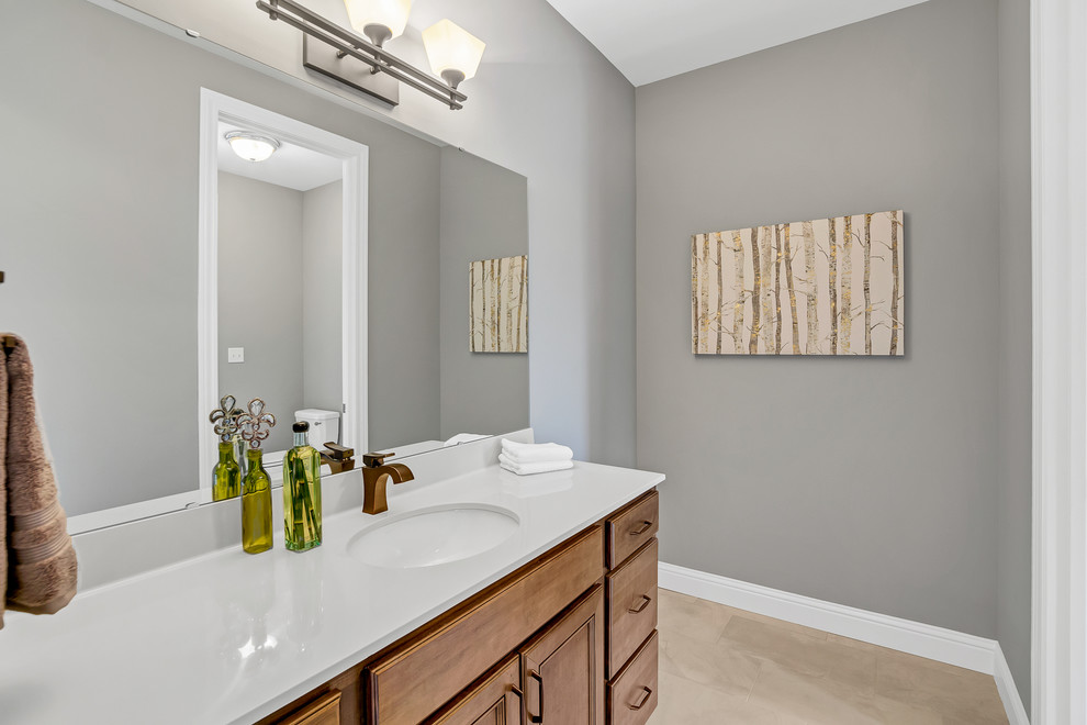 Medium sized classic family bathroom in St Louis with a built-in bath, a shower/bath combination, white tiles, ceramic tiles, a shower curtain, recessed-panel cabinets, medium wood cabinets, a two-piece toilet, grey walls, porcelain flooring, a submerged sink, engineered stone worktops and brown floors.
