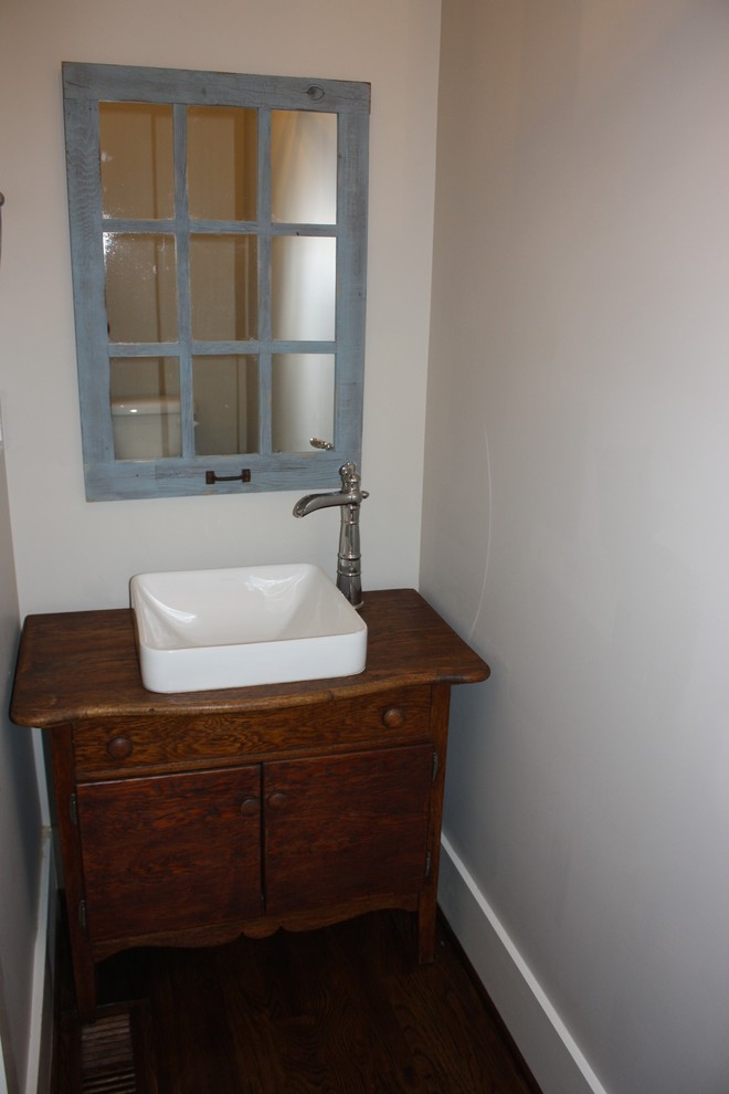 Inredning av ett badrum, med ett nedsänkt handfat, möbel-liknande, skåp i mellenmörkt trä, beige väggar och mörkt trägolv