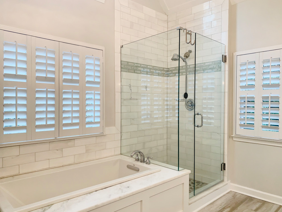 На фото: большая главная ванная комната в стиле кантри с белыми фасадами, накладной ванной, угловым душем, серыми стенами, светлым паркетным полом, серым полом и душем с распашными дверями