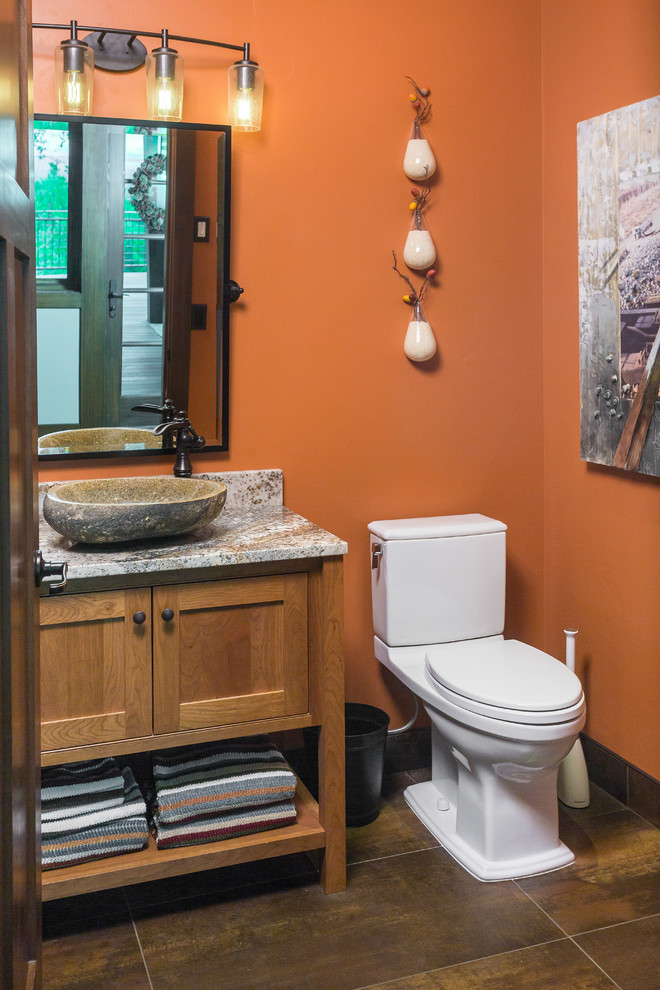 Réalisation d'une petite salle d'eau chalet en bois brun avec un placard en trompe-l'oeil, WC séparés, un mur orange, un sol en carrelage de céramique, une vasque, un plan de toilette en granite et un sol marron.