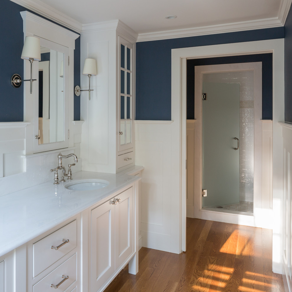 Bild på ett vintage en-suite badrum, med luckor med profilerade fronter, vita skåp, en dusch i en alkov, en toalettstol med separat cisternkåpa, blå väggar, mellanmörkt trägolv, ett undermonterad handfat och marmorbänkskiva