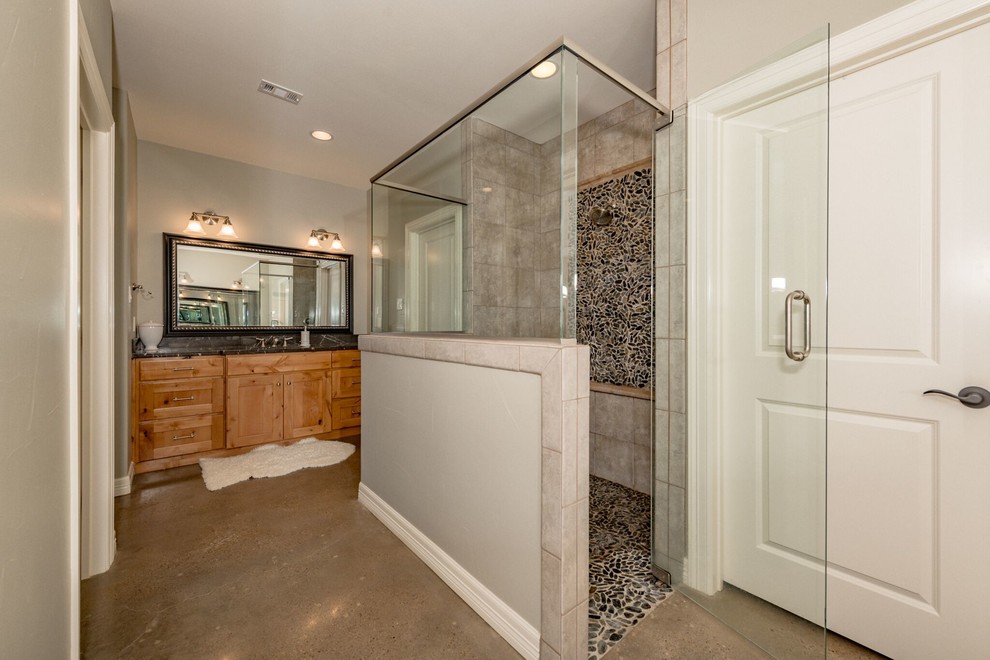 This is an example of a medium sized ensuite bathroom in Austin with shaker cabinets, light wood cabinets, an alcove shower, a two-piece toilet, beige tiles, travertine tiles, beige walls, concrete flooring, a submerged sink, marble worktops, grey floors and a hinged door.