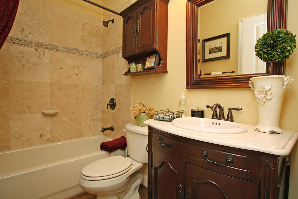 Idéer för ett mellanstort klassiskt flerfärgad en-suite badrum, med luckor med infälld panel, skåp i mörkt trä, ett badkar i en alkov, en dusch/badkar-kombination, en toalettstol med separat cisternkåpa, beige kakel, gula väggar, klinkergolv i porslin, ett undermonterad handfat, granitbänkskiva, beiget golv och dusch med duschdraperi
