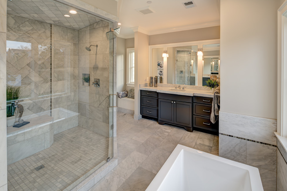 Large classic ensuite bathroom in DC Metro with recessed-panel cabinets, dark wood cabinets, a freestanding bath, a corner shower, grey tiles, marble tiles, beige walls, marble flooring, a submerged sink, marble worktops, grey floors, a hinged door and grey worktops.