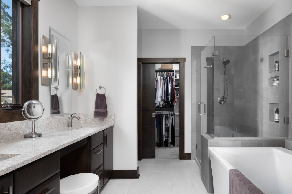 Inspiration for a large classic ensuite bathroom in Milwaukee with flat-panel cabinets, dark wood cabinets, a freestanding bath, a walk-in shower, grey walls, porcelain flooring, granite worktops, grey floors, a hinged door, grey worktops and a submerged sink.