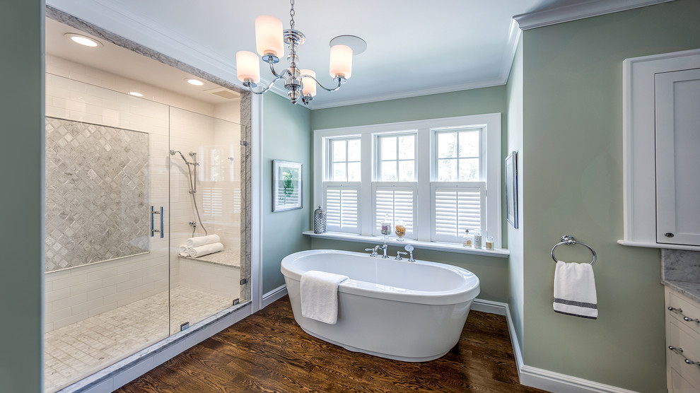 Inredning av ett klassiskt stort en-suite badrum, med ett undermonterad handfat, släta luckor, vita skåp, marmorbänkskiva, ett fristående badkar, en dubbeldusch, en toalettstol med separat cisternkåpa, vit kakel, porslinskakel, gröna väggar och mörkt trägolv