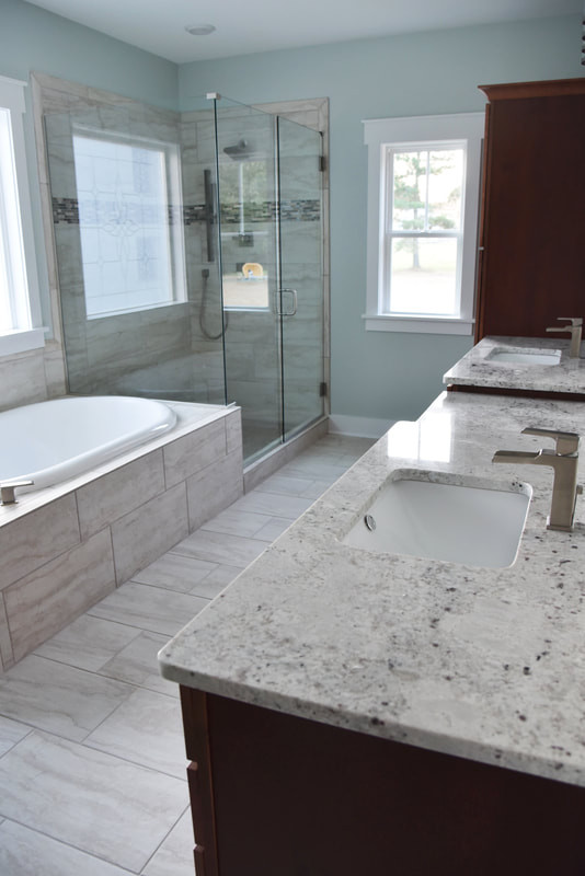 This is an example of a large traditional ensuite bathroom in Raleigh with shaker cabinets, brown cabinets, a built-in bath, a corner shower, beige tiles, ceramic tiles, blue walls, ceramic flooring, a submerged sink, granite worktops, a hinged door and multi-coloured worktops.