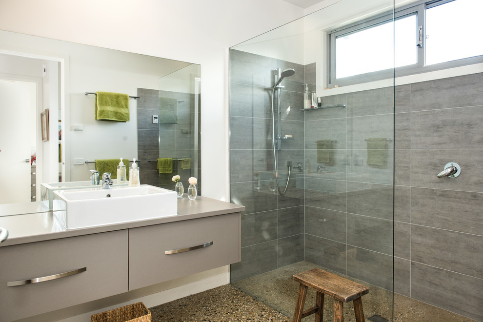 Стильный дизайн: главная ванная комната в стиле модернизм с плоскими фасадами, серыми фасадами, угловым душем, унитазом-моноблоком, белой плиткой, каменной плиткой, белыми стенами, бетонным полом, раковиной с несколькими смесителями, столешницей из искусственного кварца, разноцветным полом и открытым душем - последний тренд
