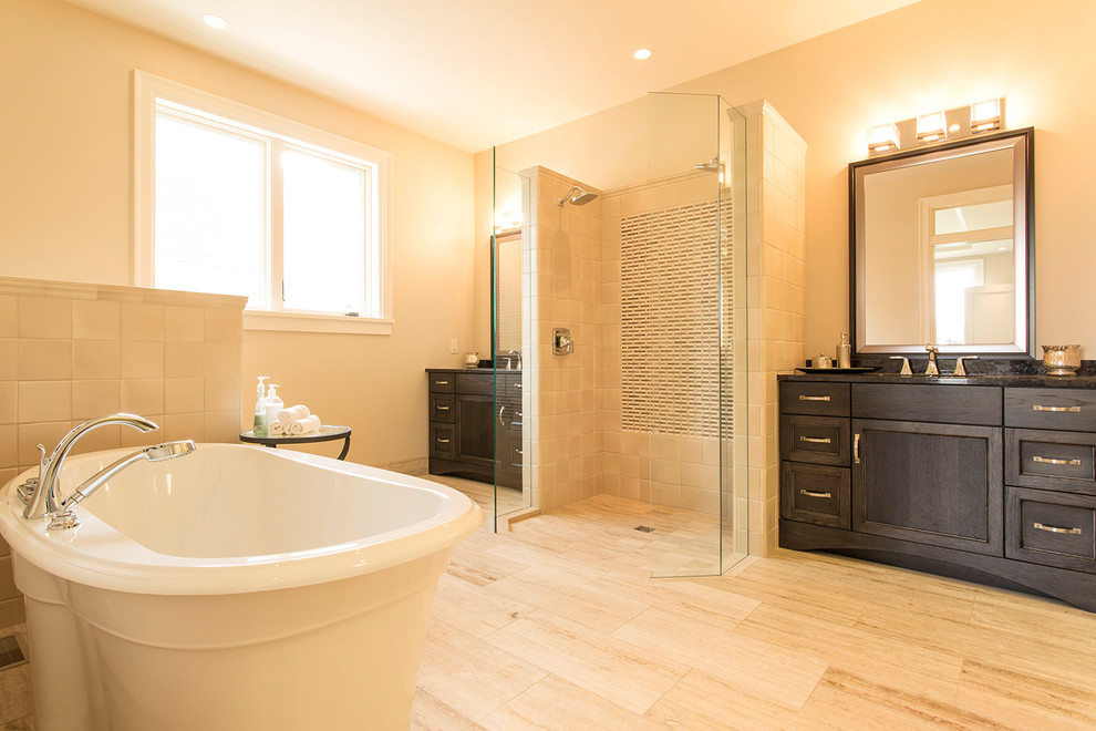 Photo of a medium sized classic ensuite bathroom in Other with shaker cabinets, dark wood cabinets, a freestanding bath, a built-in shower, beige tiles, grey tiles, porcelain tiles, beige walls, porcelain flooring, a submerged sink, granite worktops, beige floors and an open shower.