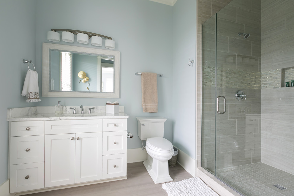 Exemple d'une salle de bain bord de mer de taille moyenne avec un placard à porte shaker, des portes de placard blanches, WC séparés, un carrelage gris, des carreaux en allumettes, un mur bleu, un sol en carrelage de porcelaine, un lavabo encastré, un plan de toilette en quartz modifié, un sol marron et une cabine de douche à porte battante.