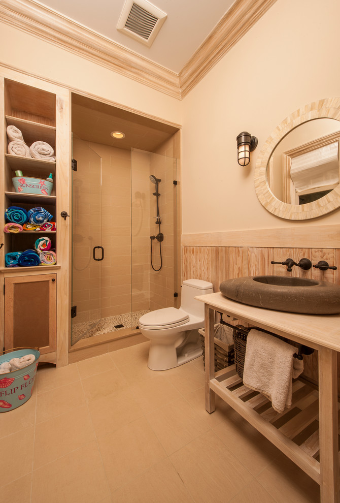Elegant beige tile alcove shower photo in Raleigh with a vessel sink, furniture-like cabinets, light wood cabinets and a one-piece toilet