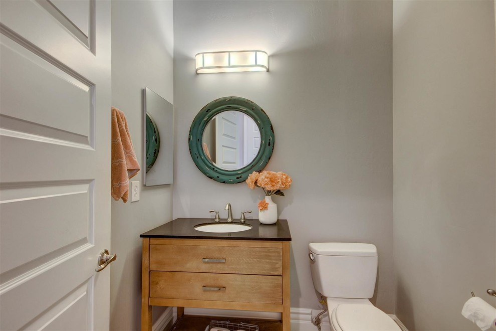Réalisation d'une petite salle d'eau craftsman en bois clair avec un placard à porte plane, WC à poser, un mur gris, un lavabo encastré et un plan de toilette en surface solide.