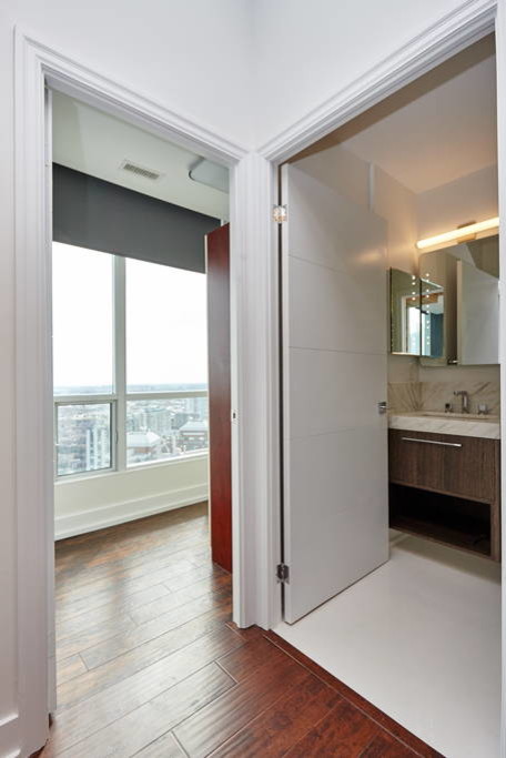 Small modern shower room bathroom in Toronto with flat-panel cabinets, dark wood cabinets, an alcove shower, a bidet, beige tiles, white tiles, stone tiles, white walls, marble flooring, a vessel sink and onyx worktops.