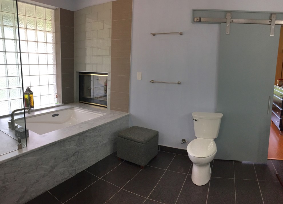 Photo of a large classic ensuite bathroom in New Orleans with an integrated sink, flat-panel cabinets, grey cabinets, engineered stone worktops, a hot tub, a corner shower, a one-piece toilet, beige tiles, porcelain tiles, grey walls and porcelain flooring.