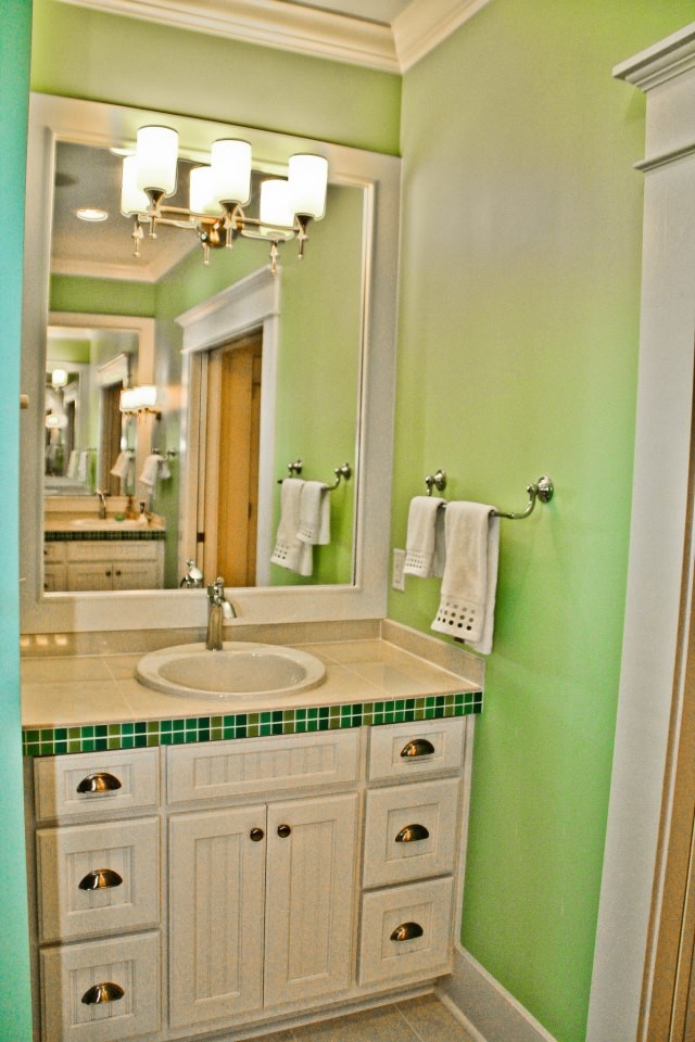 Ispirazione per una stanza da bagno con doccia chic di medie dimensioni con ante con riquadro incassato, ante bianche, piastrelle beige, piastrelle verdi, piastrelle in ceramica, pareti verdi, pavimento con piastrelle in ceramica, lavabo da incasso e top piastrellato