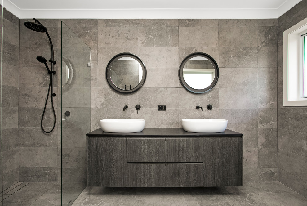 Esempio di una stanza da bagno contemporanea con ante lisce, ante grigie, piastrelle grigie, lavabo a bacinella, pavimento grigio, top nero e due lavabi