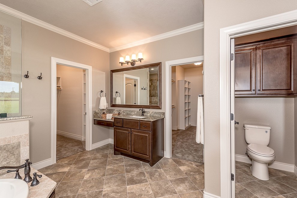 Example of a mid-sized mountain style master brown tile and travertine tile brick floor and brown floor bathroom design in Austin with shaker cabinets, medium tone wood cabinets, a two-piece toilet, beige walls, an undermount sink and granite countertops