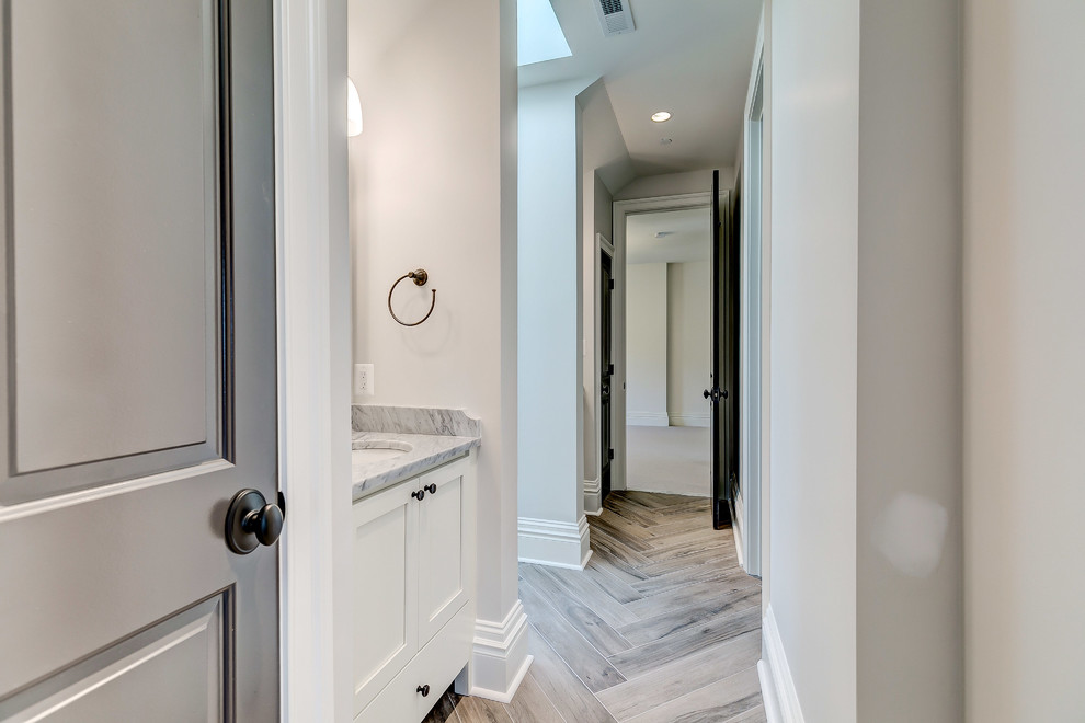 Ispirazione per una stanza da bagno minimal di medie dimensioni con ante in stile shaker, ante bianche, pareti grigie, parquet chiaro, lavabo sottopiano e top in marmo