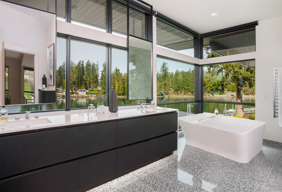 Inspiration for an expansive contemporary ensuite bathroom in Seattle with flat-panel cabinets, black cabinets, a freestanding bath, white walls, terrazzo flooring, a submerged sink, grey floors, white worktops, double sinks and a floating vanity unit.