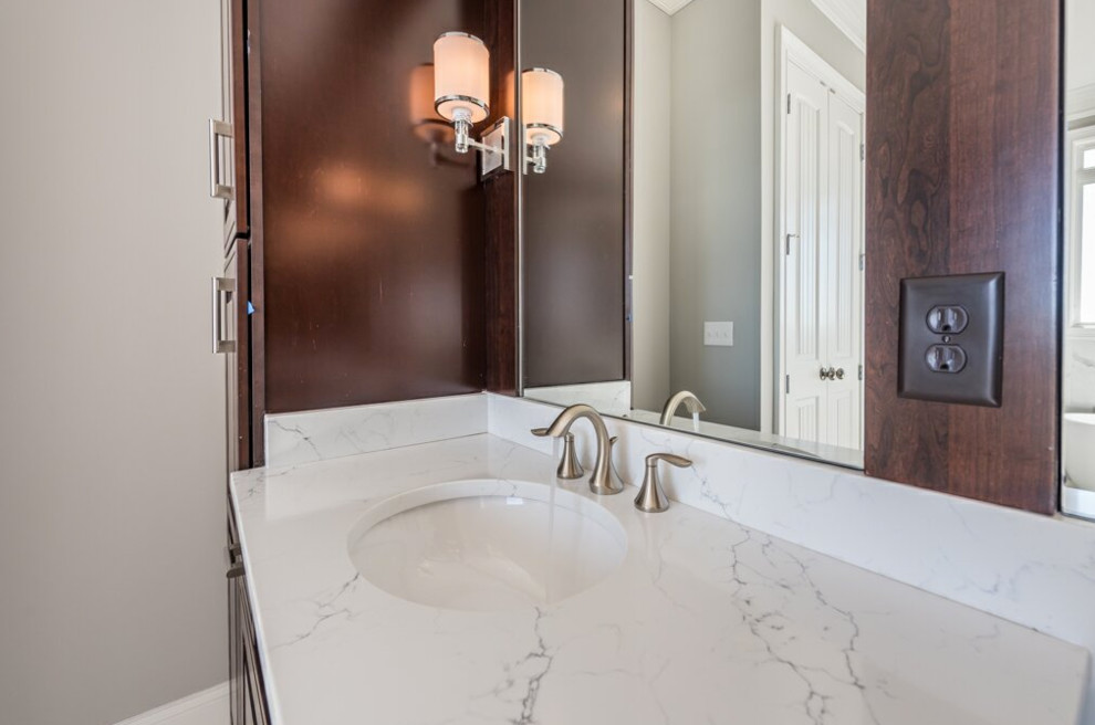 Inredning av ett klassiskt stort en-suite badrum, med skåp i mellenmörkt trä, ett fristående badkar, en dusch i en alkov, grå kakel, vit kakel, porslinskakel, grå väggar, klinkergolv i porslin, ett undermonterad handfat, marmorbänkskiva, vitt golv, dusch med gångjärnsdörr och luckor med upphöjd panel