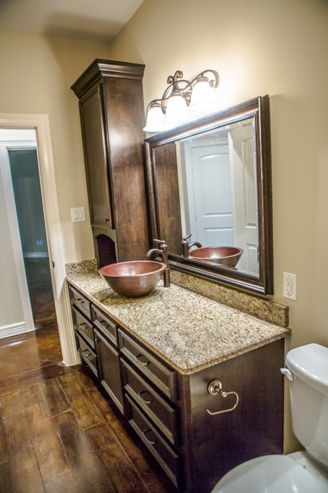 Inredning av ett mellanstort en-suite badrum, med ett fristående handfat, luckor med profilerade fronter, vita skåp, granitbänkskiva, ett hörnbadkar, en dusch i en alkov, brun kakel, beige väggar och betonggolv
