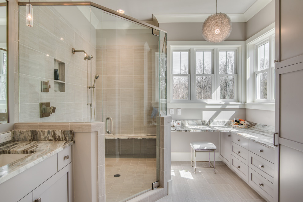 Cette image montre une salle de bain traditionnelle avec un placard à porte shaker, des portes de placard grises, un carrelage beige, un mur gris, un lavabo encastré et une cabine de douche à porte battante.
