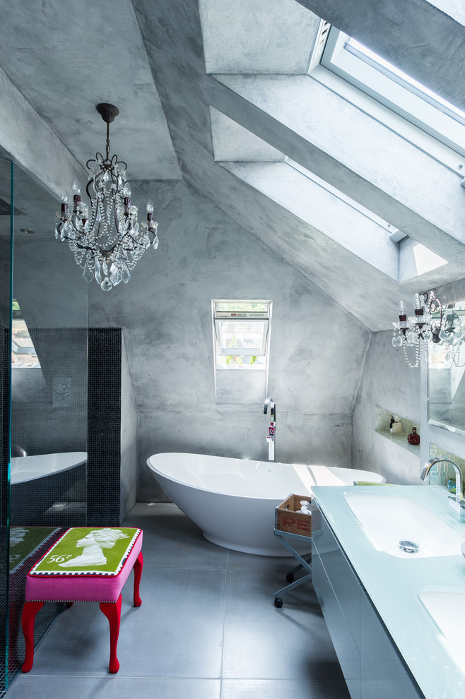 На фото: главная ванная комната в современном стиле с врезной раковиной, плоскими фасадами, отдельно стоящей ванной, душем без бортиков, серыми стенами, бетонным полом и стеклянной столешницей с