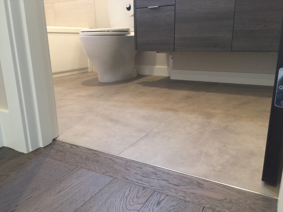 Small minimalist 3/4 gray tile and porcelain tile ceramic tile and gray floor bathroom photo in Seattle with flat-panel cabinets, dark wood cabinets, a one-piece toilet, gray walls, an undermount sink and solid surface countertops