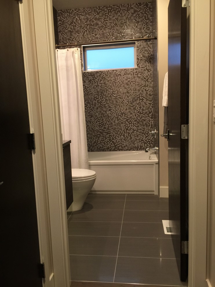 На фото: ванная комната среднего размера в современном стиле с плоскими фасадами, темными деревянными фасадами, ванной в нише, душем над ванной, унитазом-моноблоком, черно-белой плиткой, стеклянной плиткой, бежевыми стенами, серым полом и шторкой для ванной с