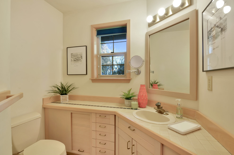 На фото: большая ванная комната в современном стиле с фасадами с выступающей филенкой, светлыми деревянными фасадами, унитазом-моноблоком, бежевыми стенами, полом из керамической плитки, душевой кабиной, монолитной раковиной, столешницей из плитки, бежевым полом и белой столешницей с