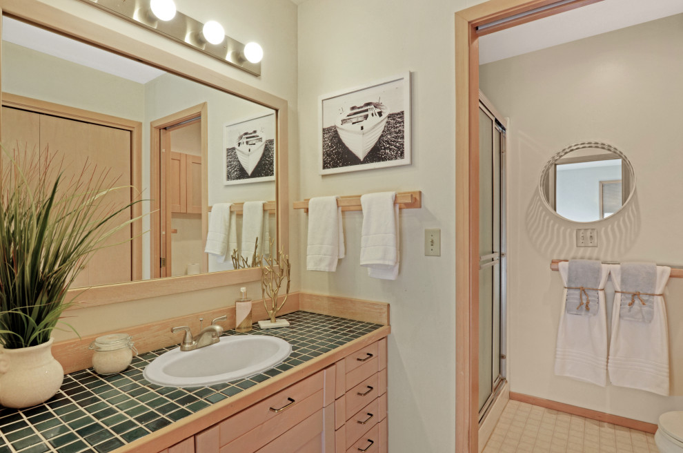 Large contemporary ensuite bathroom in Seattle with raised-panel cabinets, light wood cabinets, a walk-in shower, a one-piece toilet, beige walls, ceramic flooring, an integrated sink, tiled worktops, beige floors, a sliding door and green worktops.