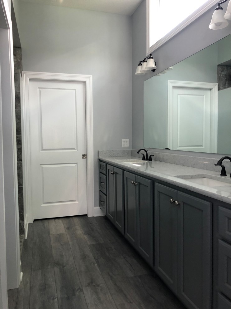 Idéer för att renovera ett mellanstort amerikanskt grå grått en-suite badrum, med luckor med infälld panel, grå skåp, en öppen dusch, en toalettstol med hel cisternkåpa, flerfärgad kakel, keramikplattor, grå väggar, mellanmörkt trägolv, ett undermonterad handfat, bänkskiva i kvarts, brunt golv och med dusch som är öppen