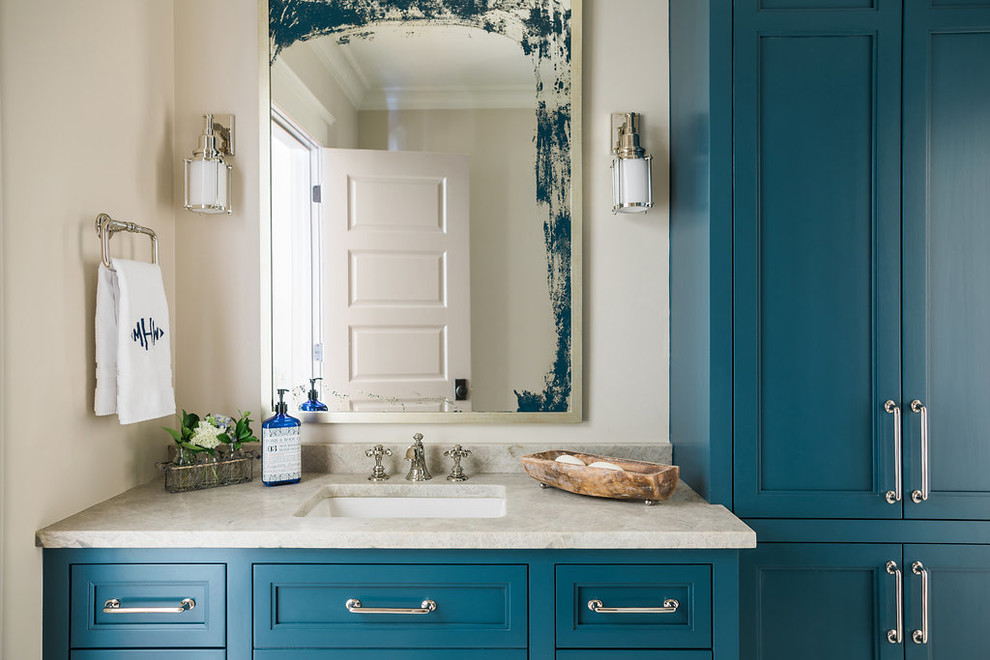 Ejemplo de cuarto de baño costero con armarios con paneles empotrados, puertas de armario azules, paredes beige, lavabo bajoencimera, encimera de granito y encimeras beige