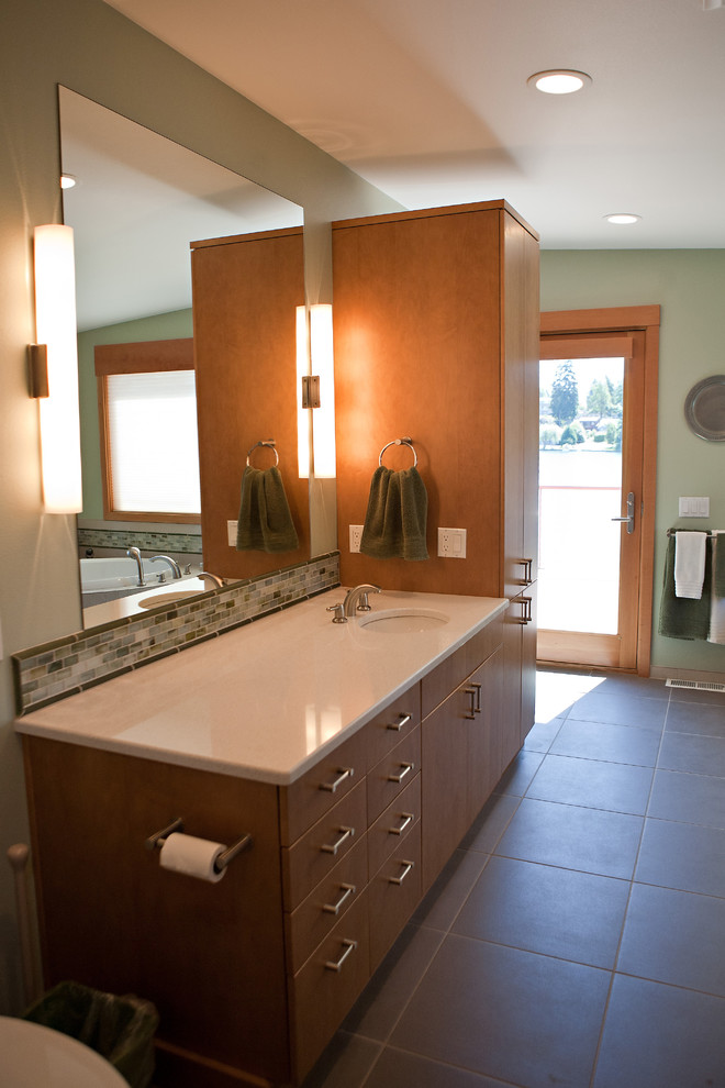 На фото: большая главная ванная комната в современном стиле с врезной раковиной, плоскими фасадами, светлыми деревянными фасадами, столешницей из искусственного кварца, серой плиткой, керамогранитной плиткой и полом из керамогранита