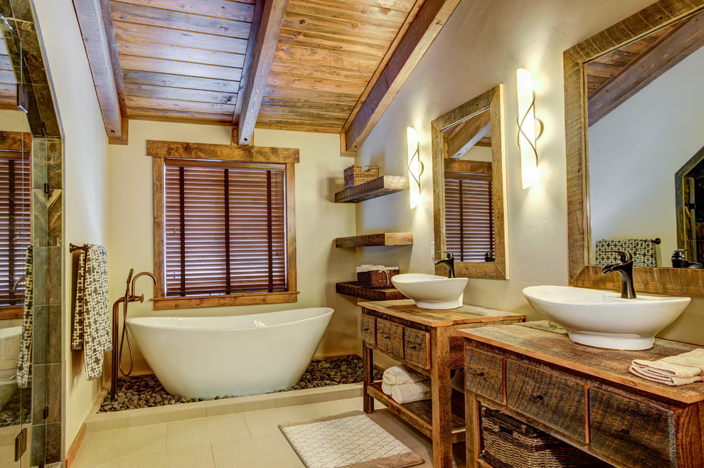 Cette image montre une grande douche en alcôve principale chalet en bois vieilli avec une baignoire indépendante, un mur beige, un sol en carrelage de céramique, un lavabo de ferme et un plan de toilette en bois.