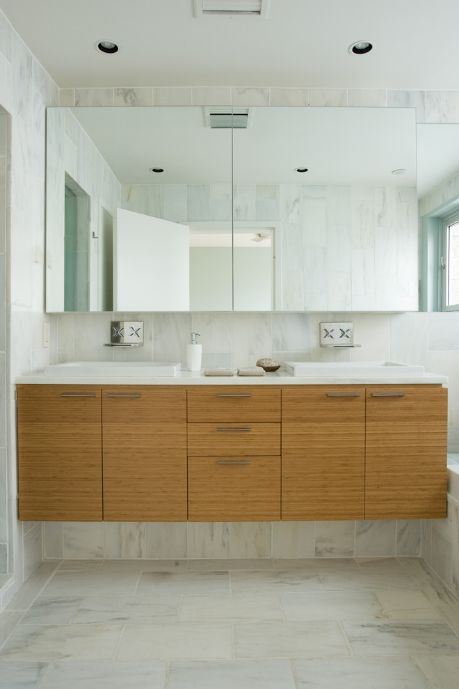 Aménagement d'une salle de bain contemporaine en bois brun avec un plan de toilette en marbre, un placard à porte plane et du carrelage en marbre.