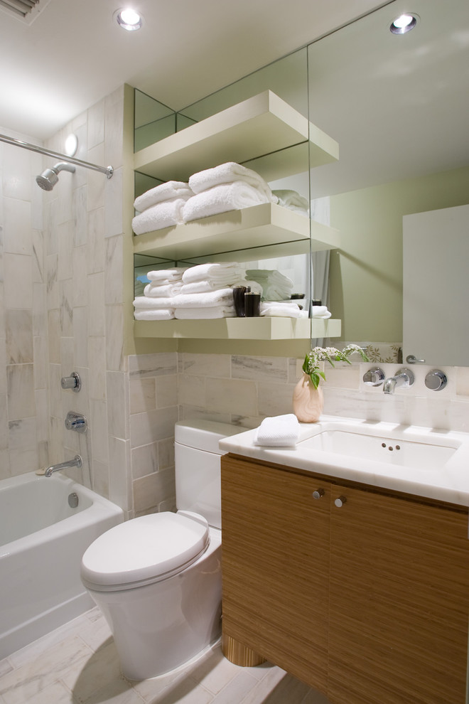 This is an example of a contemporary bathroom in Birmingham with a submerged sink, flat-panel cabinets, medium wood cabinets, an alcove bath, a shower/bath combination, a two-piece toilet and white tiles.