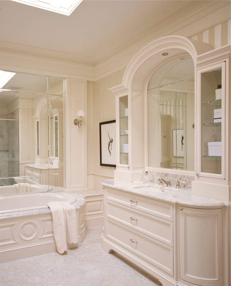 Свежая идея для дизайна: большая главная ванная комната в классическом стиле с фасадами островного типа, белыми фасадами, ванной на ножках, угловым душем, унитазом-моноблоком, серой плиткой, плиткой из листового камня, бежевыми стенами, мраморным полом, врезной раковиной и мраморной столешницей - отличное фото интерьера