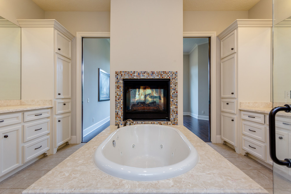 This is an example of a large mediterranean ensuite bathroom in Houston with recessed-panel cabinets, white cabinets, a built-in bath, a built-in shower, a two-piece toilet, beige tiles, travertine tiles, beige walls, travertine flooring, a submerged sink, granite worktops, beige floors, an open shower and beige worktops.