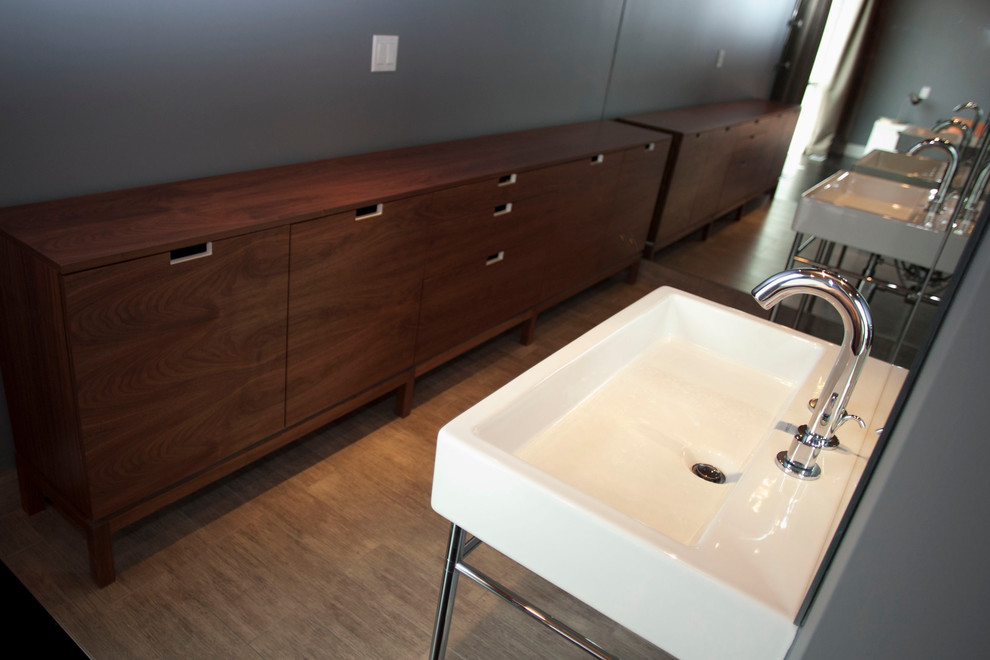 Small modern ensuite bathroom in Chicago with a two-piece toilet, grey walls, a pedestal sink, freestanding cabinets, medium wood cabinets, light hardwood flooring, a walk-in shower, grey tiles and matchstick tiles.