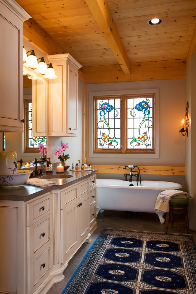 Immagine di una stanza da bagno padronale stile rurale di medie dimensioni con lavabo sottopiano, ante a filo, ante beige, vasca freestanding, pareti marroni, pavimento in ardesia e top in quarzo composito