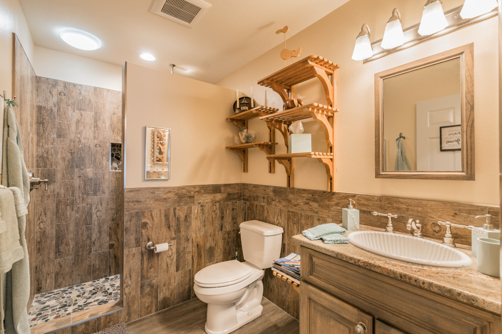Modelo de cuarto de baño campestre con bañera con patas, ducha a ras de suelo, paredes verdes, suelo laminado, encimera de granito y suelo marrón