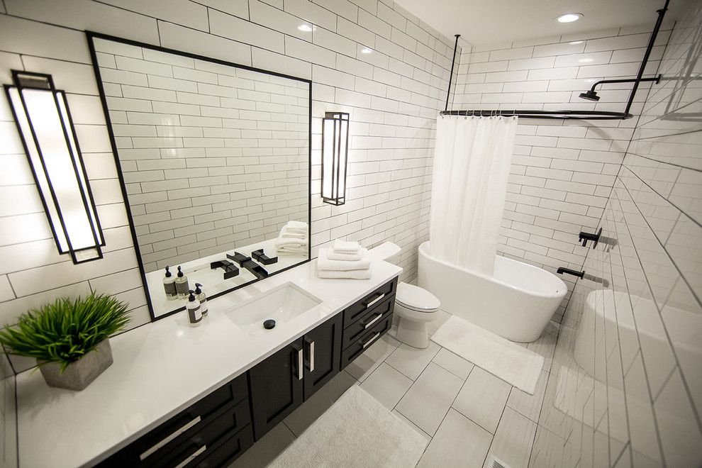 Inspiration for a mid-sized transitional 3/4 white tile and subway tile ceramic tile and gray floor bathroom remodel in Cedar Rapids with shaker cabinets, black cabinets, a two-piece toilet, white walls, an undermount sink and laminate countertops