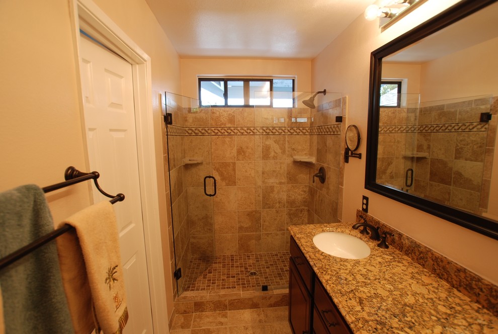 Design ideas for a medium sized mediterranean ensuite bathroom in Orange County with a submerged sink, recessed-panel cabinets, dark wood cabinets, granite worktops, an alcove shower, a two-piece toilet, beige tiles, stone tiles, white walls and porcelain flooring.